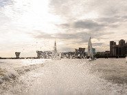 Брызги в воде от мотора на фоне парусных яхт